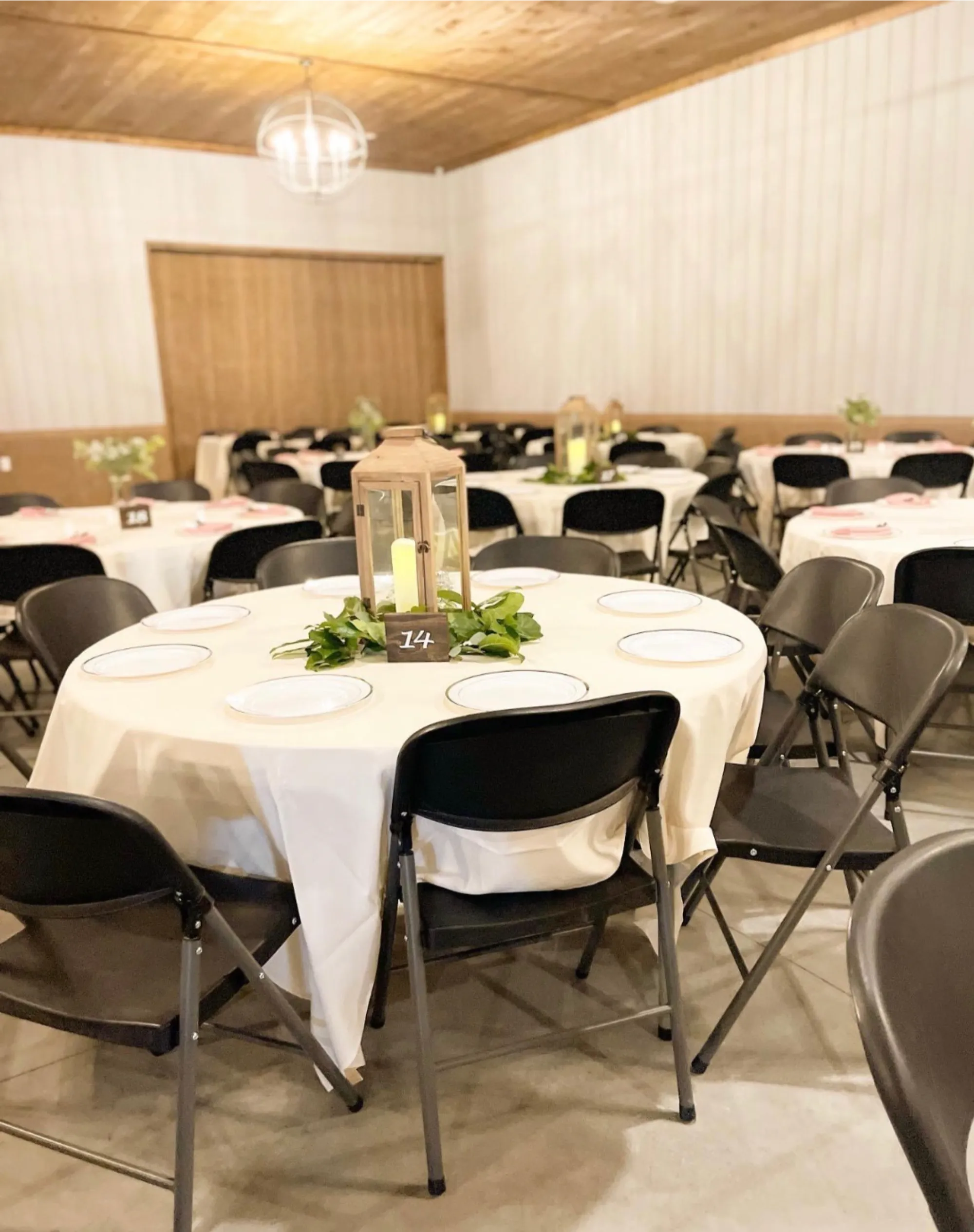 Elegant reception hall with round tables, white chairs, and warm lighting