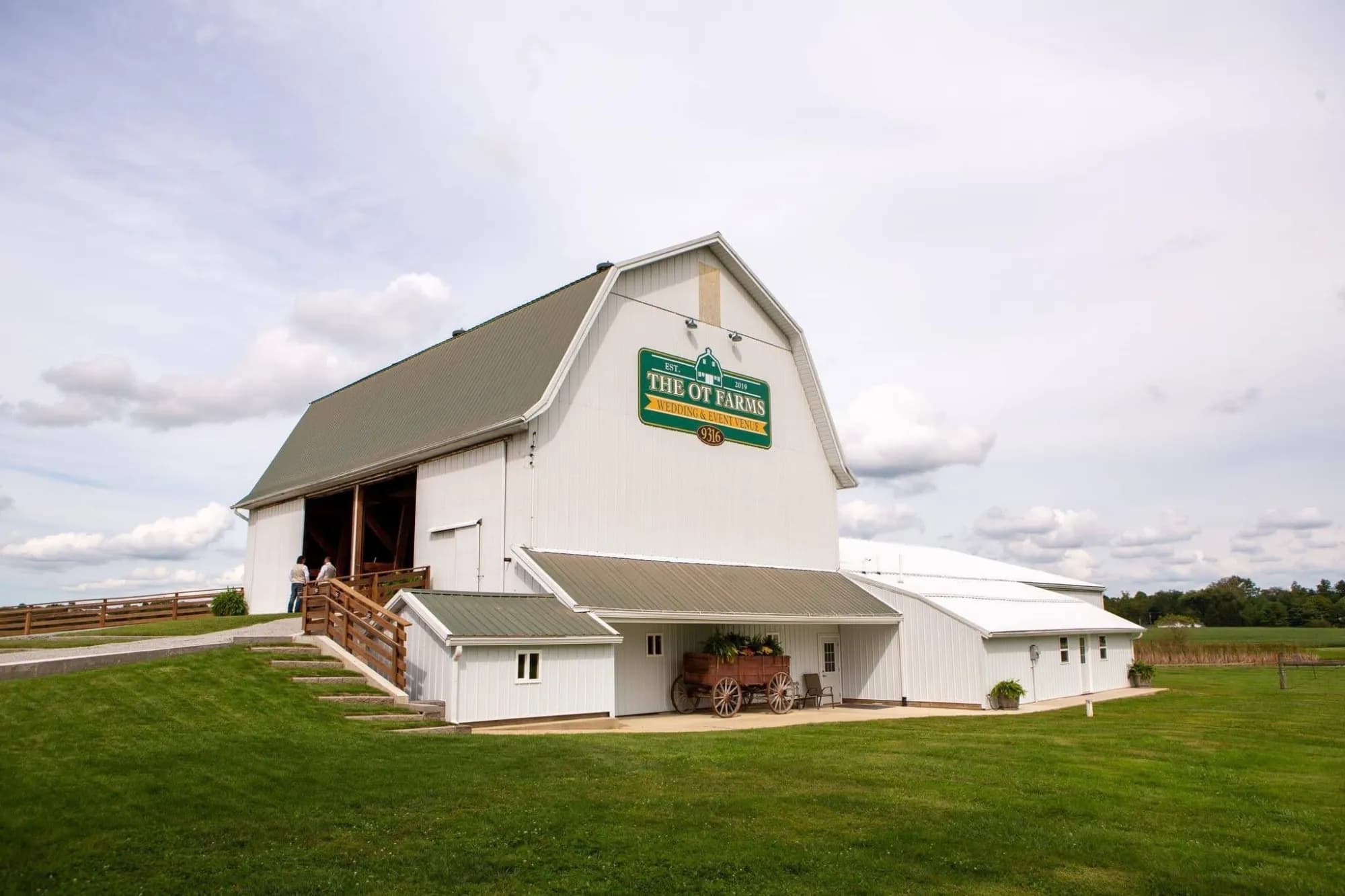 The OT Farms white barn with green roof and gravel path leading to the entrance
